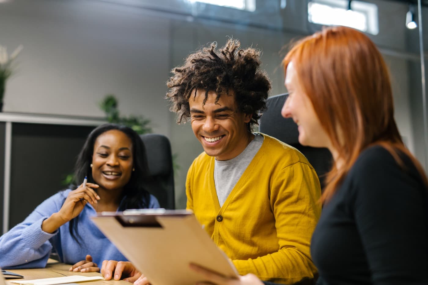 Three people smiling while working on an idea together
